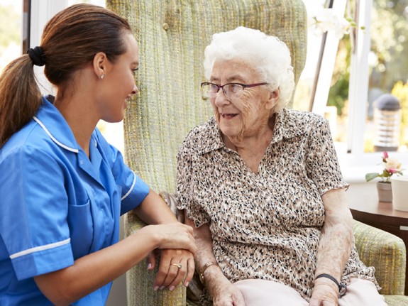 Sjuksköterska som sitter med en äldre dam. Foto:Mostphotos