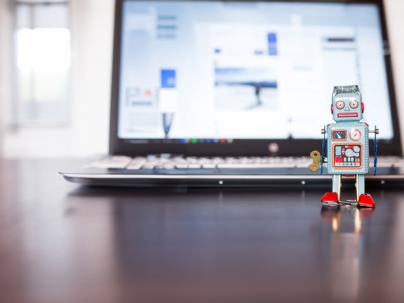 Laptop med en robotleksak ståendes framför