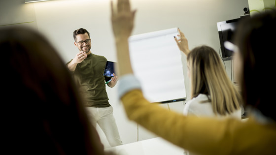 Student som räcker upp handen under en föreläsning. Foto: Mostphotos