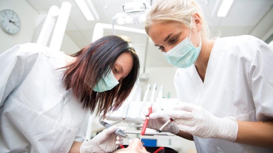 två tandläkare som jobbar med en patient. Foto:Mostphotos