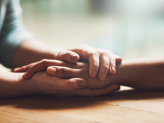 Två personer som håller om varandras händer. Foto: Mostphotos.