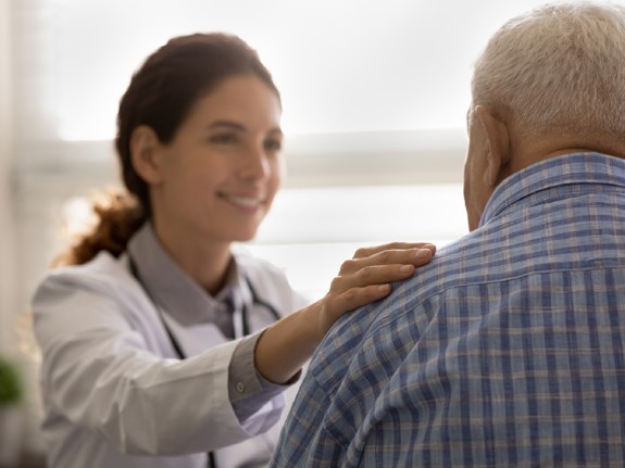 läkare håller handen på en patients axel. Foto: Mostphotos.