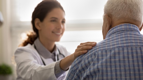 läkare håller handen på en patients axel. Foto: Mostphotos.