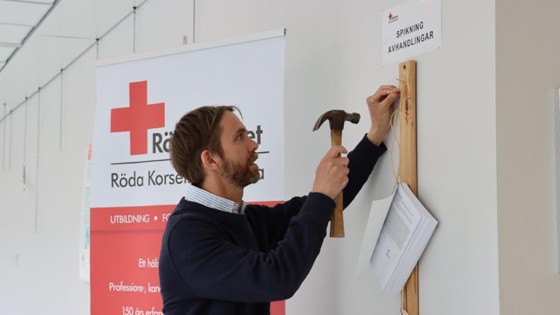 Doktoranden Andreas Malm spikade sin licentiatavhandling på Röda Korsets Högskolas vägg. Foto:RKH