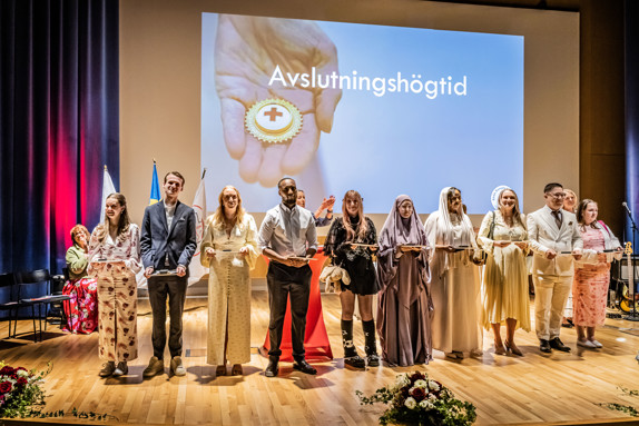 Studenter vid Röda Korsets Högskola står på scen under avslutningshögtiden. Foto: Jenny Frejing
