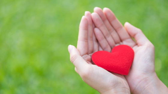 Kvinna som håller ett rött hjärta av tyg i sin hand