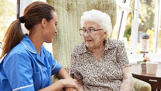 Sjuksköterska som sitter med en äldre dam. Foto:Mostphotos