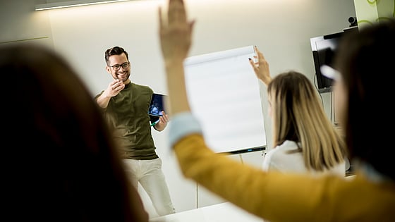 Student som räcker upp handen under en föreläsning. Foto: Mostphotos