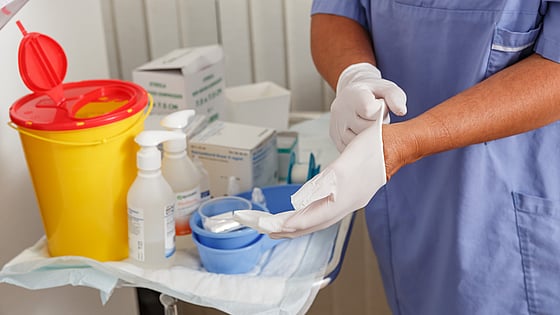 Sjuksköterska som tar på sig plasthandskar. Foto: Mostphotos