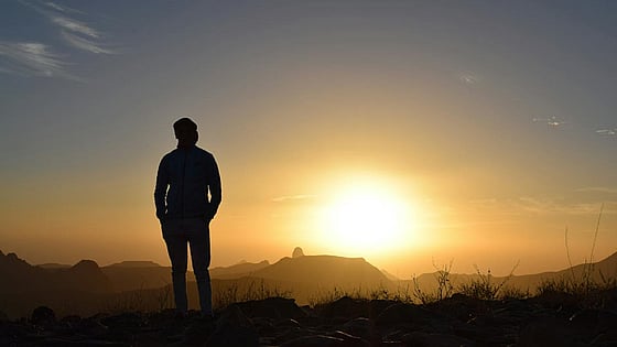 person som kollar mot solnedgång. Foto: Mostphotos
