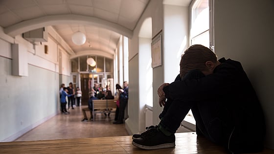 Elev som sitter med huvudet mellan benen i en skolkatalog. Foto: Mostphotos