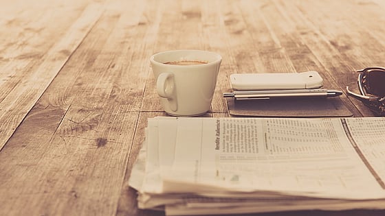 bild på ett bord med en kopp kaffe och en bunt med papper