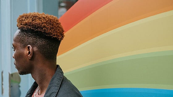 Person som står framför en regnbågsfärgad vägg. Foto: Mostphotos