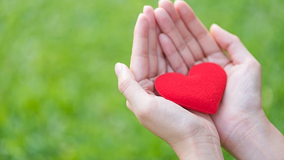 Kvinna som håller ett rött hjärta av tyg i sin hand