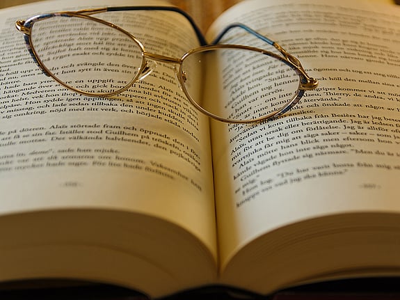 bild på en bok med glasögon ovanpå. Foto: Mostphotos.