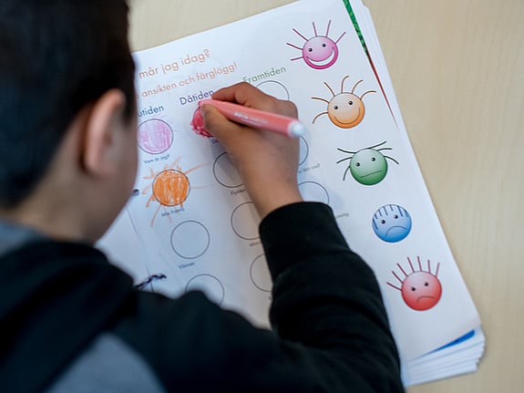 Barn som skriver med en penna. Foto:SRK