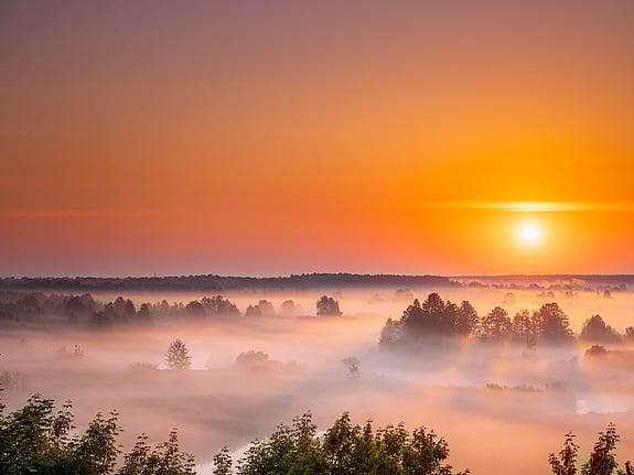 soluppgång över dimmigt landskap. Foto: Mostphotos