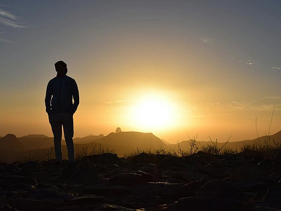 person som kollar mot solnedgång. Foto: Mostphotos