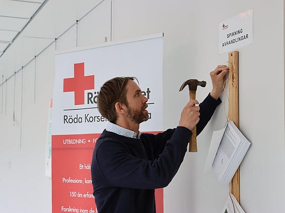 Doktoranden Andreas Malm spikade sin licentiatavhandling på Röda Korsets Högskolas vägg. Foto:RKH