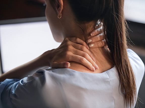 Kvinna som håller sig för nacken. Foto:Mostphotos