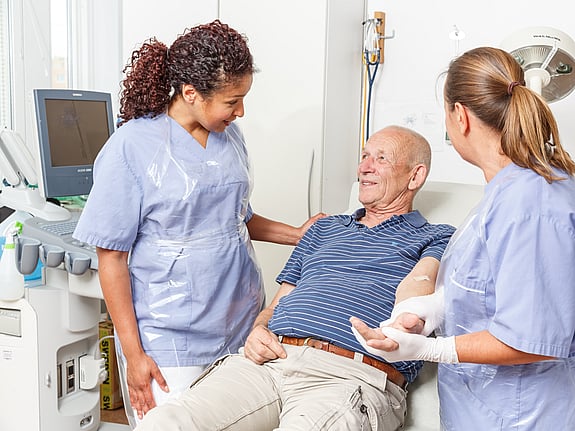 Två sjuksköterskor som hjälper en patient. Foto: Mostphotos