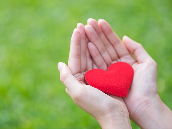 Kvinna som håller ett rött hjärta av tyg i sina händer