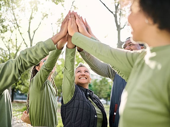 En grupp personer som highfivear i en skog. Foto: Mostphotos.
