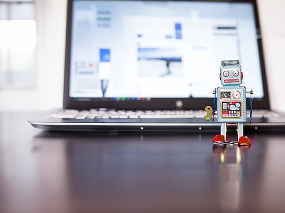 Laptop med en robotleksak ståendes framför