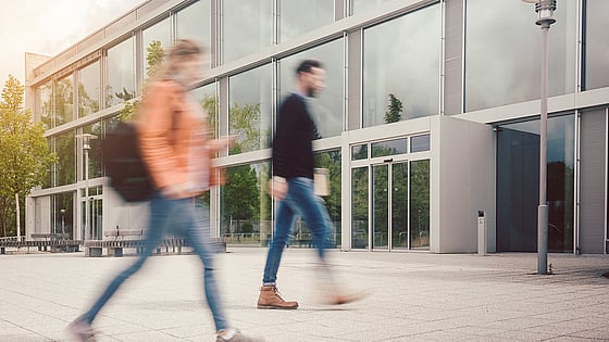 Två personer som går mot en byggnad