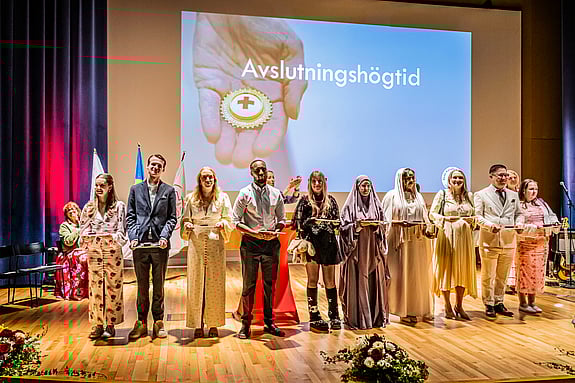 Studenter vid Röda Korsets Högskola står på scen under avslutningshögtiden. Foto: Jenny Frejing