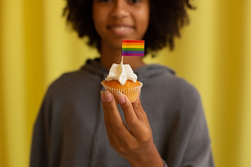 Kvinna som håller i en cupcake med pride-flagga